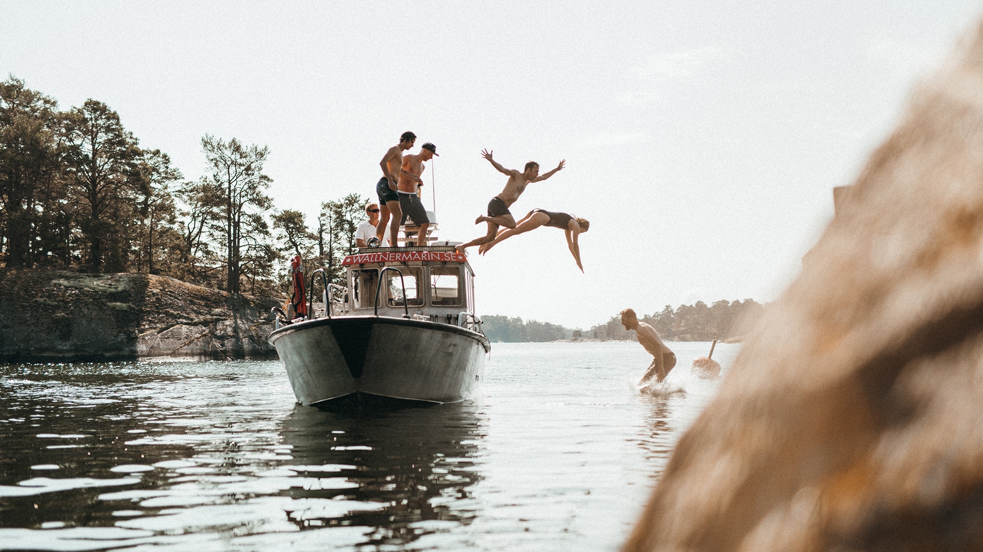 Junge Menschen springen von einem Boot in den See für die Jack Wolfskin Kampagne #GOBACKPACK