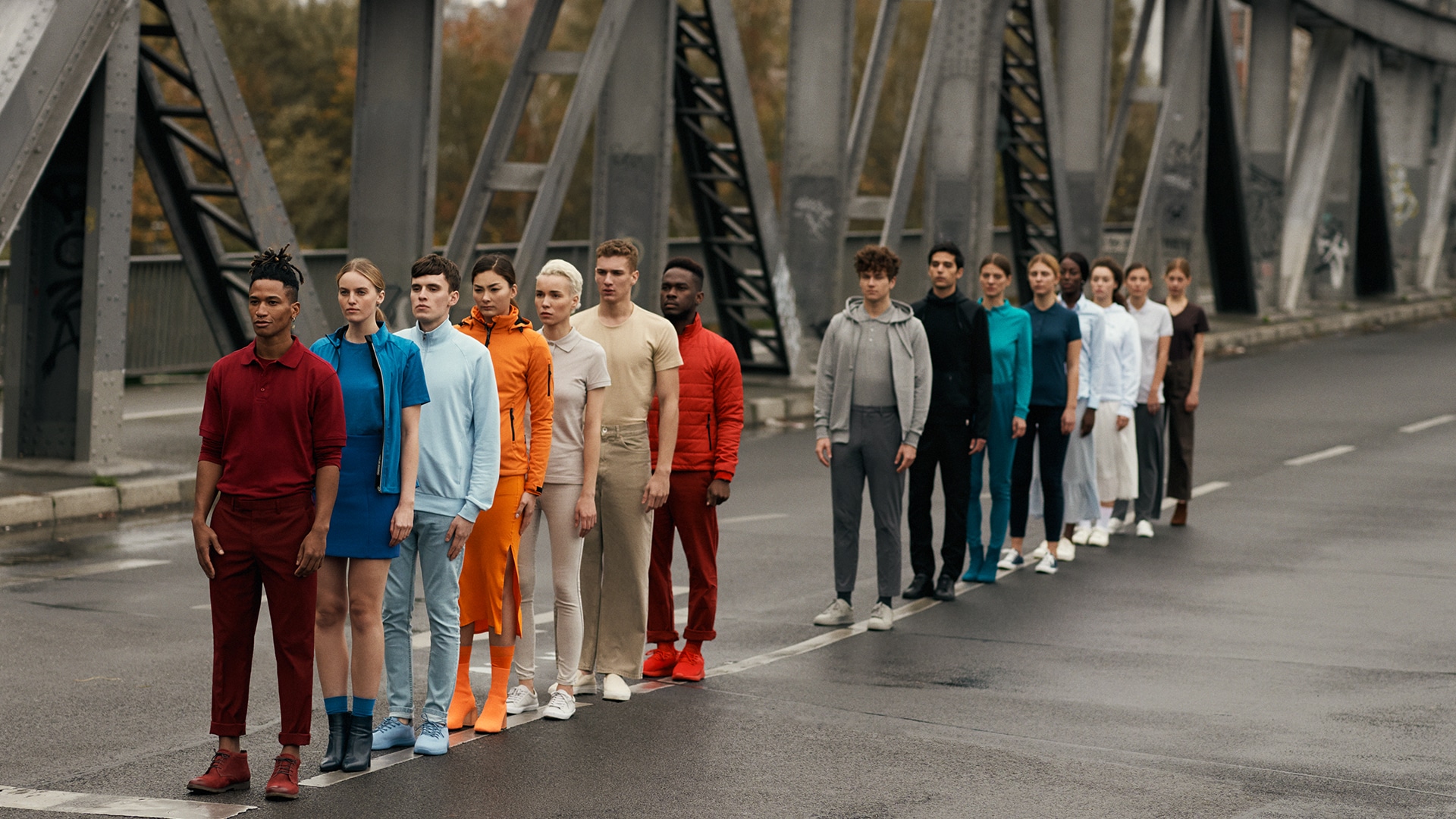 Bunt gekleidete Menschen stehen in einer Reihe auf einer Brücke für das Hakro Inspirations Shooting