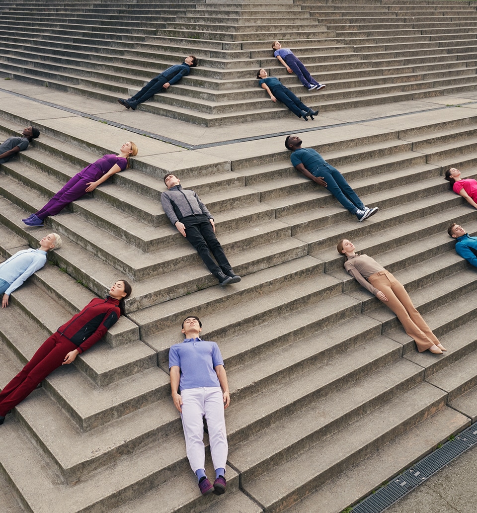 Bunt gekleidete Menschen liegen auf einer Treppe für das Hakro Inspirations Shooting