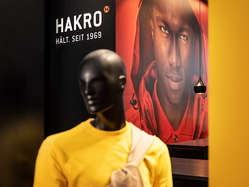 Hakro Messestand mit einer Schaufensterpuppe die ein gelbes Shirt trägt