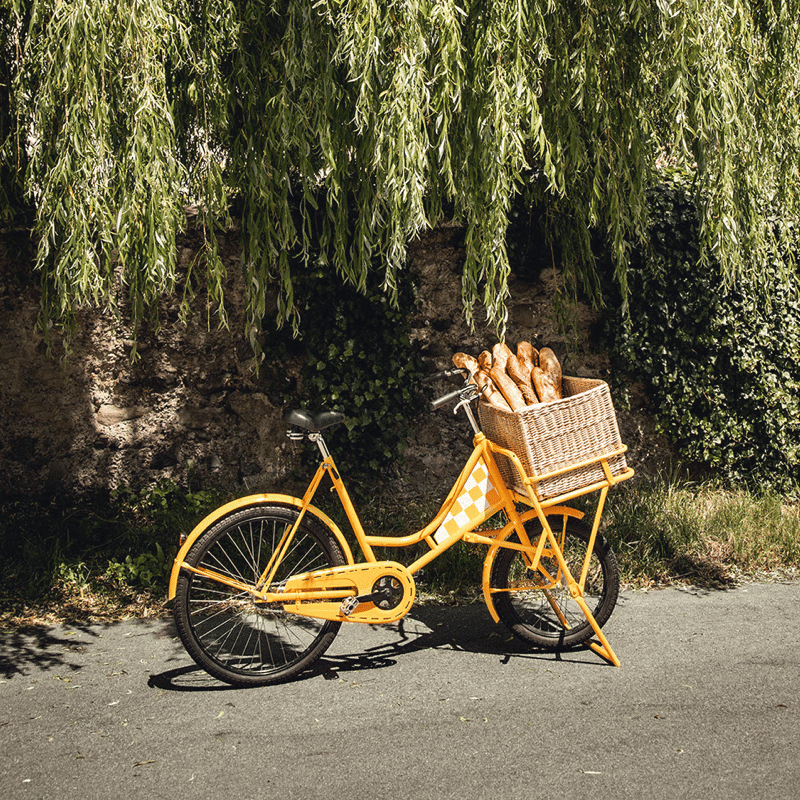 Vor einer grünbewachsenen Mauer steht ein gelbes Fahrrad mit einem Brotkorb auf dem Gepäckträger für den Markenrelaunch der Bäckerei Ruetz