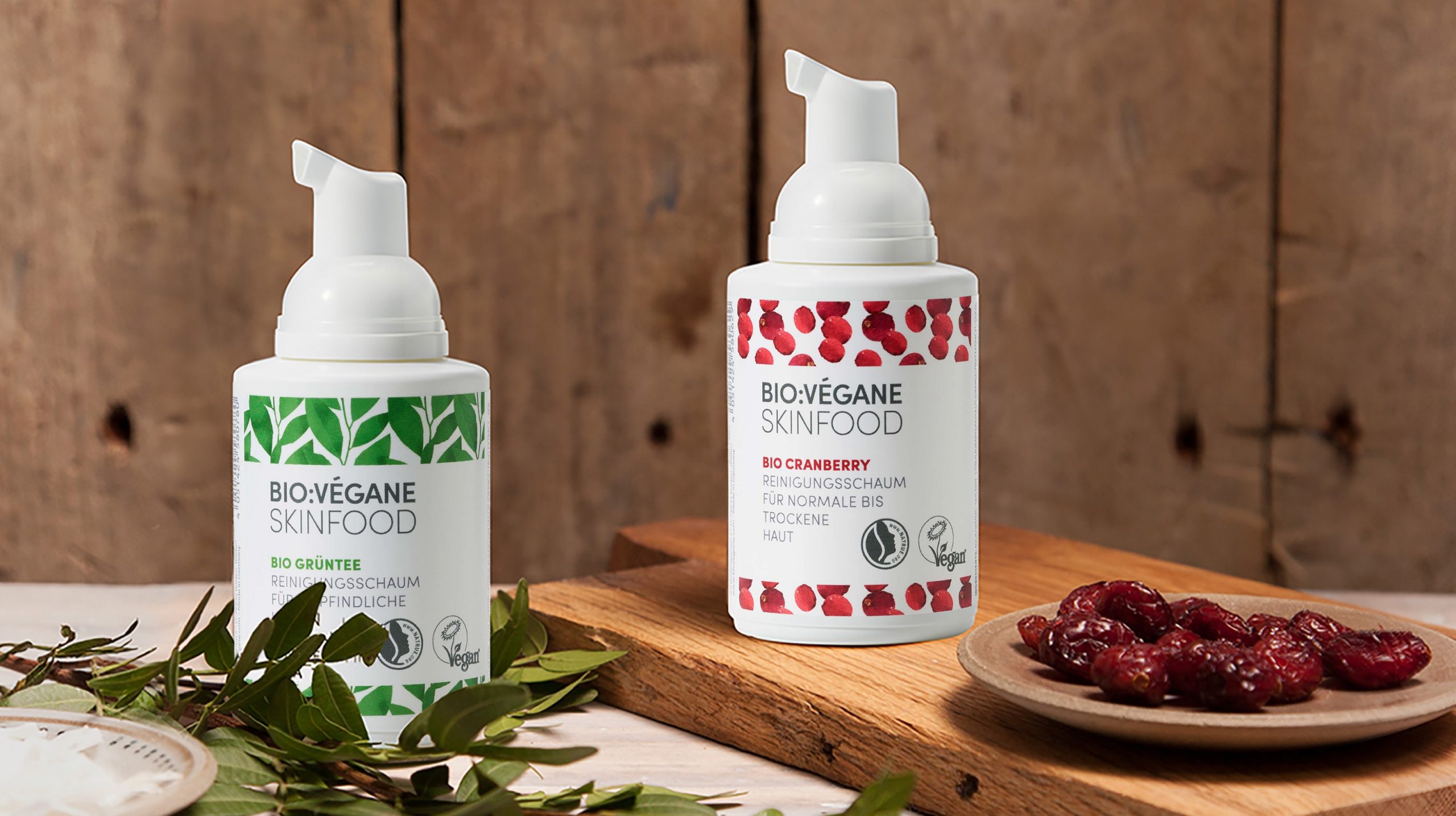 Bio.Vegane Grüntee und Cranberry Reinigungsschaum stehen auf einem Holzbrett mit einer Schale Cranberries im Rahmen der Bio.Vegane Kampagne