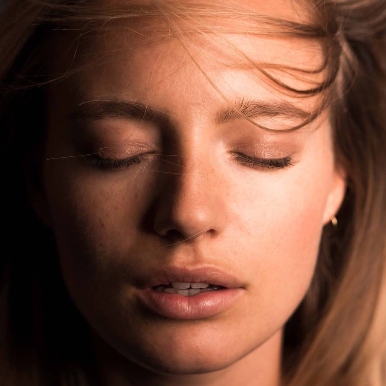 junge Frau hat die Augen geschlossen und ihre Haare wehen im Gesicht im Rahmen der Bio.Vegane Kampagne