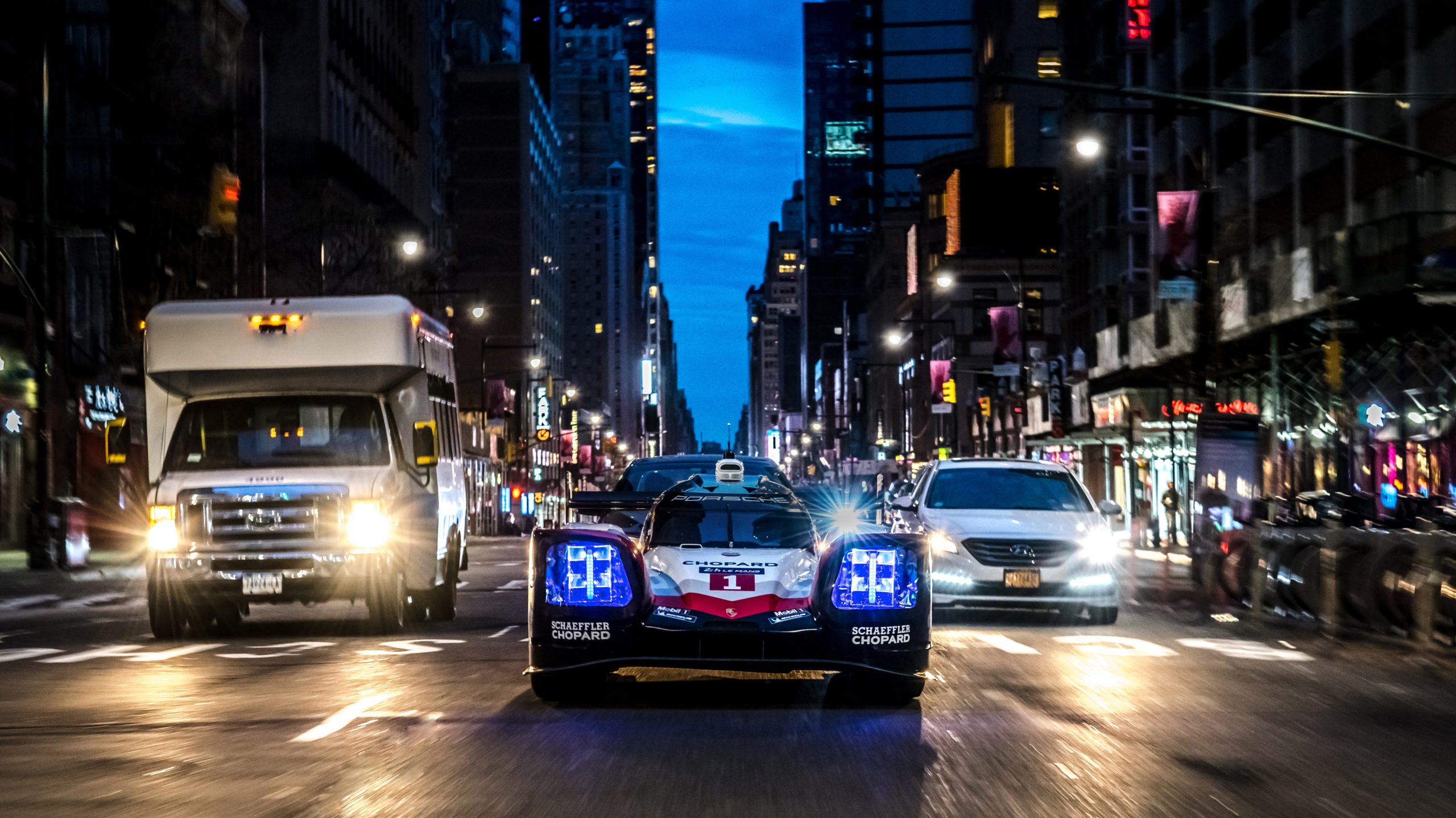 Porsche 919 auf einer Stadtstraße mit Autos links und rechts