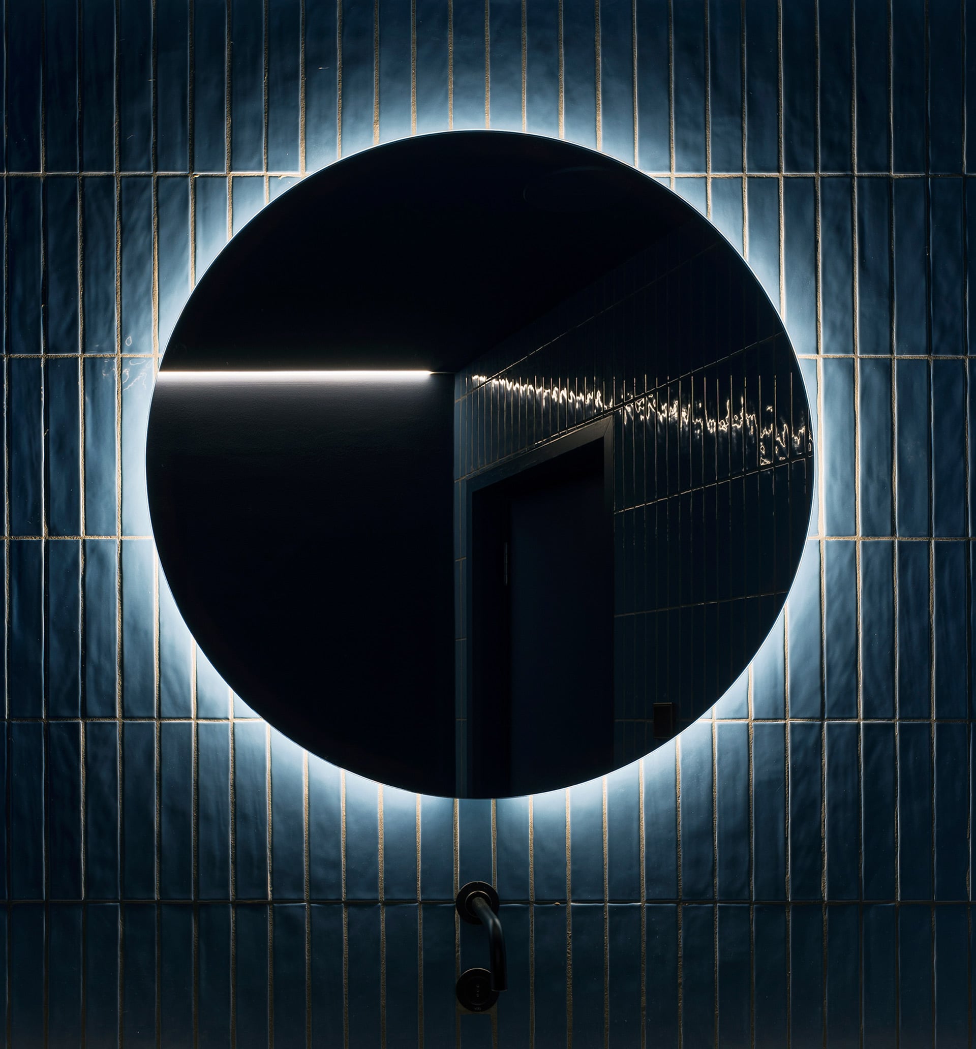 Dunkler gefliester Raum mit rundem Spiegel an der Wand