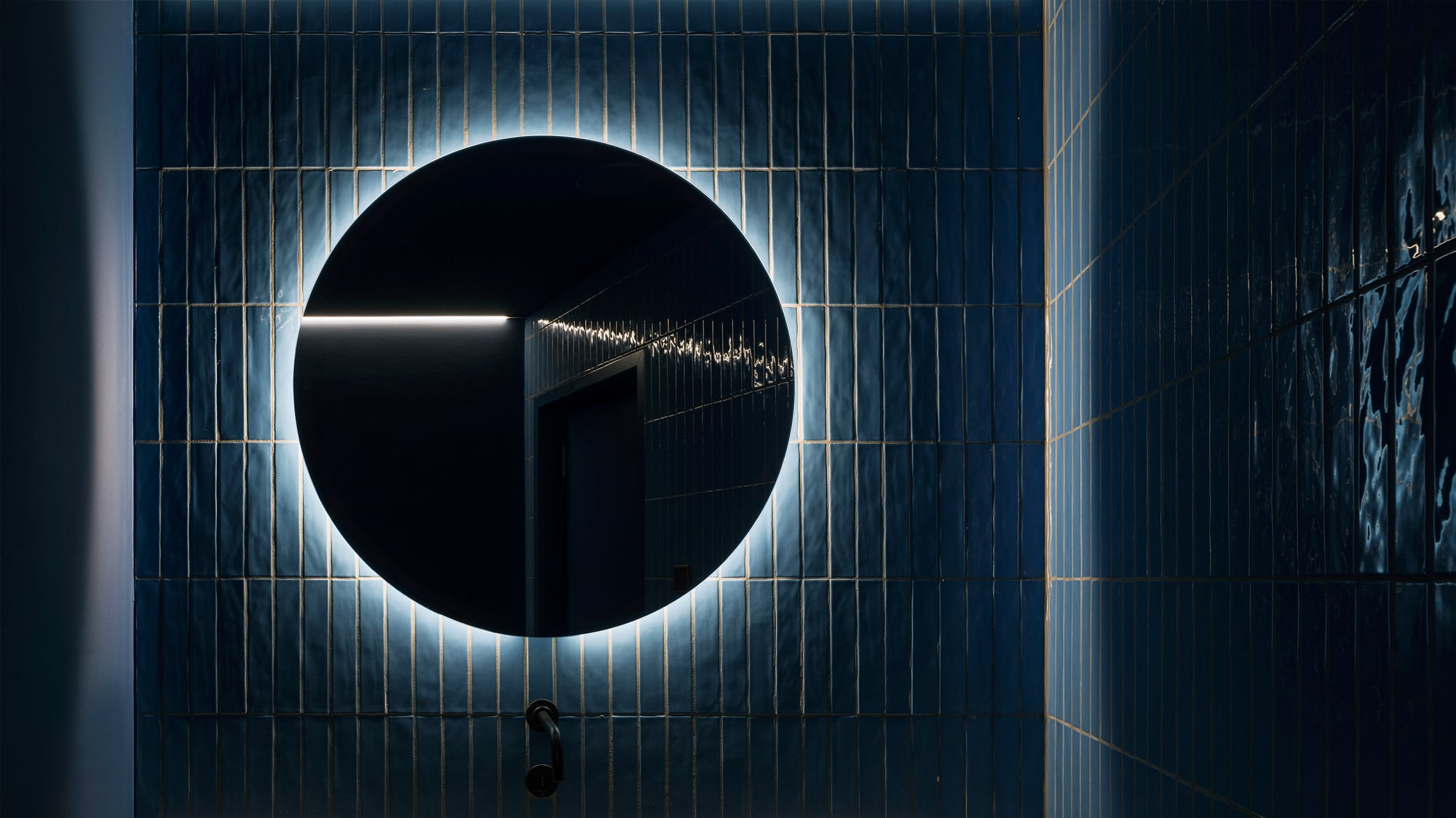 Dunkler gefliester Raum mit rundem Spiegel an der Wand